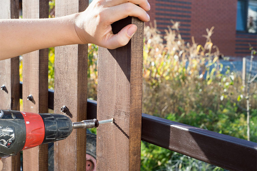 man installing wooden fence outside